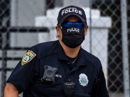 A police officer wears a mask amid fears over the spread of the novel coronavirus (COVID-19) while standing guard at a "Freedom Rally" protest in support of opening Florida in South Beach in Miami, on May 10, 2020. (Photo by CHANDAN KHANNA / AFP) (Photo by CHANDAN KHANNA/AFP via Getty …