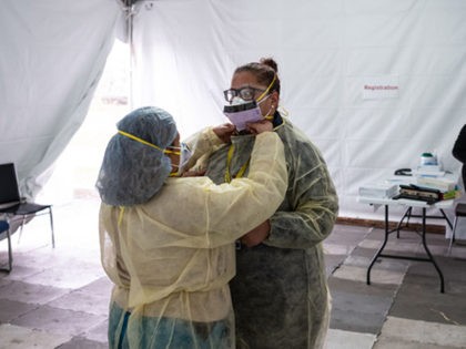 NEW YORK, NY - MARCH 20: Nurses adjust protective masks inside a testing tent at St. Barnabas hospital on March 20, 2020 in New York City. St. Barnabas hospital in the Bronx set-up tents to triage possible COVID-19 patients outside before they enter the main Emergency department area. (Photo by …