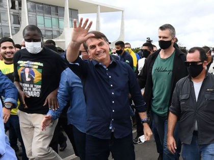 Brazil's President Jair Bolsonaro greets supporters upon arrival at Planalto Palace in Brasilia, on May 24, 2020, amid the COVID-19 coronavirus pandemic. - Despite positive signs elsewhere, the disease continued its surge in large parts of South America, with the death toll in Brazil passing 22,000 and infections topping 347,000, …