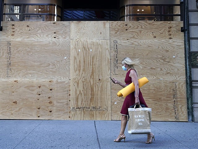 TOPSHOT - A woman walks by a boarded up Cartier store on 5th Avenue in New York City June 8, 2020. - Today New York City enters "Phase 1" of a four-part reopening plan after spending more than two months under lockdown. New York City is the final region in …