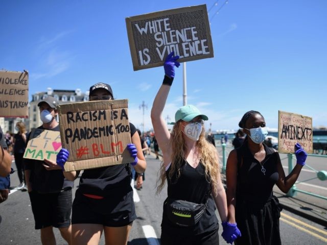 Protesters hold up placards as they march along the seafront in support of the Black Lives Matter movement at a protest action in Brighton, on the south coast of England on June 13, 2020, in the aftermath of the death of unarmed black man George Floyd in police custody in …