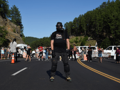 Activists and members of different tribes from the region block the road to Mount Rushmore National Monument with vans as they protest and confront police and military personnel in Keystone, South Dakota on July 3, 2020, during a demonstration around the Mount Rushmore National Monument and the visit of US …
