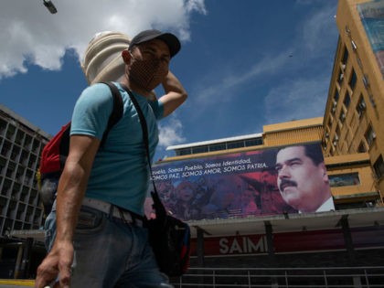 CARACAS, VENEZUELA - JULY 06: A man wearing a face mask walks in front of an image of Venezuela's president Nicolas Maduro in Downtown Caracas on July 6, 2020 in Caracas, Venezuela. Venezuela resumes today a total lockdown after a week of easing measures. The country will apply a so-called …