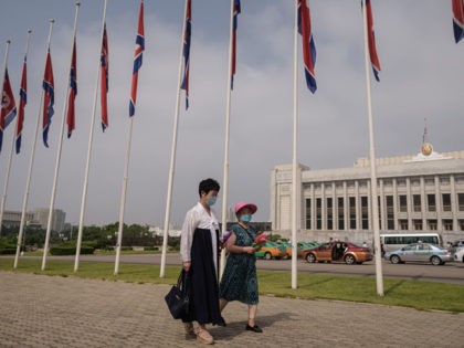 Two women wearing face masks walk past a row of North Korean flags to pay their respects on the occasion of 26th anniversary of Kim Il Sung's death, at Mansu hill in Pyongyang on July 8, 2020. (Photo by KIM Won Jin / AFP) (Photo by KIM WON JIN/AFP via …