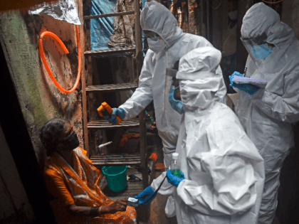 Medical volunteers wearing Personal Protective Equipment (PPE) gear take temperature reading of a woman as they conduct a door-to-door medical screening inside Dharavi slums to fight against the spread of the COVID-19 coronavirus, in Mumbai on July 9, 2020. - India's major cities have been worst hit by the pandemic. …