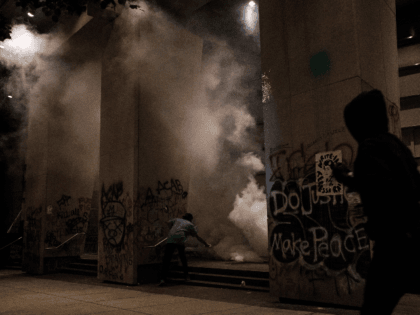 PORTLAND, OR - JULY 17: Protestors run as tear gas is deployed on the steps of the U.S. Di