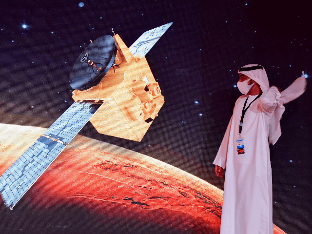 An Emirati walks past a screen displaying the "Hope" Mars probe at the Mohammed Bin Rashid