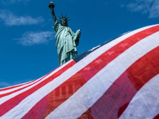 NEW YORK, NY - JULY 20: The Statue of Liberty is seen over a wind blown American flag scar