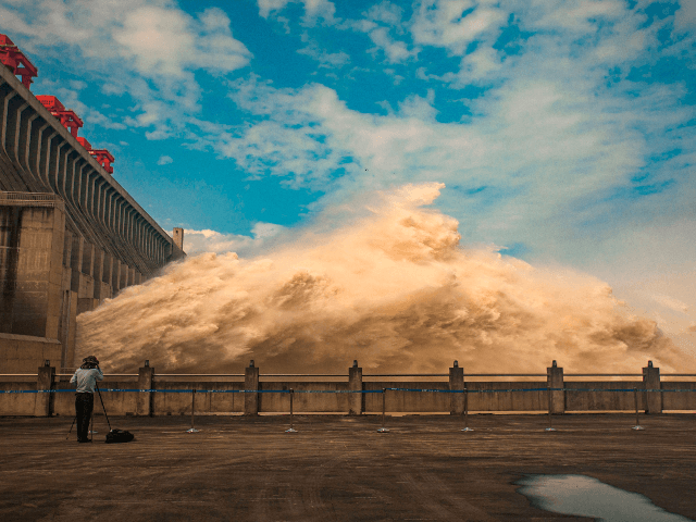 This photo taken on July 19, 2020 shows a person taking photos while water is released from the Three Gorges Dam, a gigantic hydropower project on the Yangtze river, to relieve flood pressure in Yichang, central China's Hubei province. - Rising waters across central and eastern China have left over …