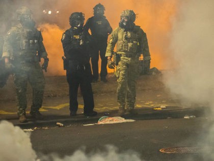 PORTLAND, OR - JULY 21: Federal police walk through tear gas while dispersing a crowd of a