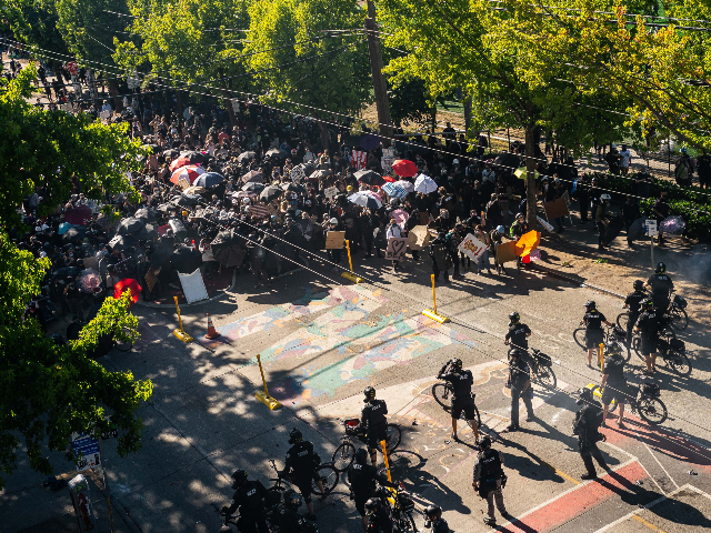 Police push demonstrators back atop a Black Lives Matter street mural in the area formerly