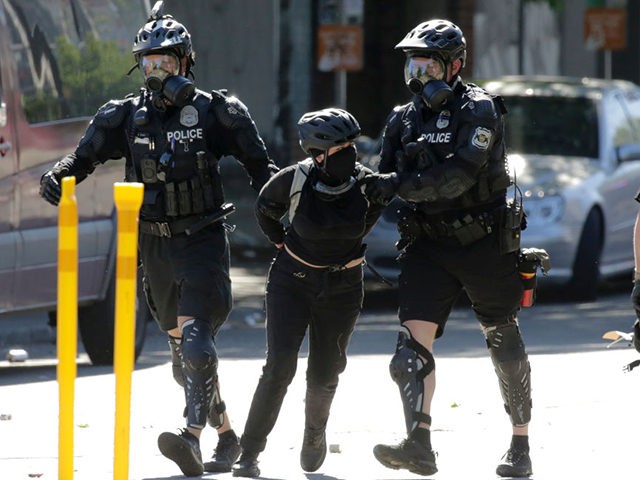 Seattle police officers arrest a protester during a "Youth Day of Action and Solidarity with Portland" demonstration in Seattle, Washington on July 25, 2020. - Police in Seattle used flashbang grenades and pepper spray Saturday against protesters who set fire to construction trailers outside a youth jail, amid a wave …