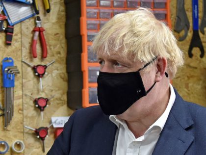 Britain's Prime Minister Boris Johnson wearing a black face mask featuring a number '10', due to the COVID-19 pandemic, talks to the owner of the the Cycle Lounge, Rodney Rouse, a bicycle repair shop in Beeston, central England, on July 28, 2020, during an event to launch the the government's …