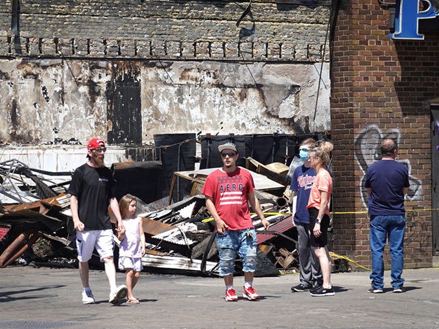 MINNEAPOLIS, MINNESOTA - JUNE 03: People walk past the charred remains of a pawn shop dest