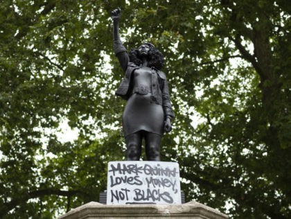 BRISTOL, ENGLAND - JULY 15: A sign saying "Marc Quinn loves money not blacks" is placed on a new sculpture, by local artist Marc Quinn, of Black Lives Matter protestor Jen Reid on the plinth where the Edward Colston statue used to stand on July 15, 2020 in Bristol, England. …