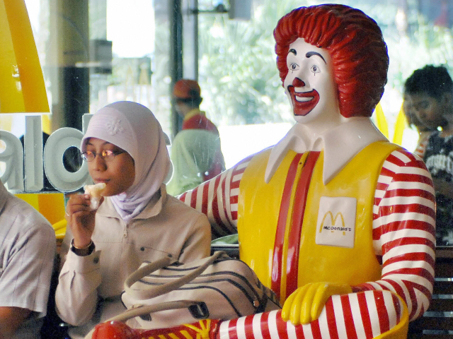 Yogyakarta, INDONESIA: A Muslim woman eats ice cream next to a statue of Ronald McDonald i