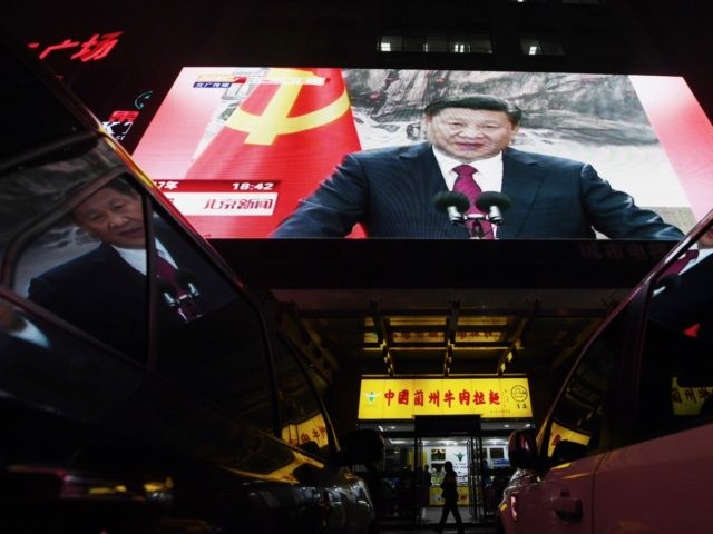 TOPSHOT - People walk outside a shop below a screen showing news coverage about Chinese President Xi Jinping, in Beijing on October 25, 2017. Chinese President Xi Jinping was formally handed a second term on October 25, 2017, with no clear successor emerging in a revamped ruling council, cementing his …