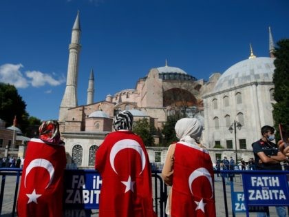 People, draped in Turkish flags, gather outside the Byzantine-era Hagia Sophia, one of Istanbul's main tourist attractions in the historic Sultanahmet district of Istanbul, following Turkey's Council of State's decision, Friday, July 10, 2020.Turkey's Council of State, threw its weight behind a petition brought by a religious group and annulled …