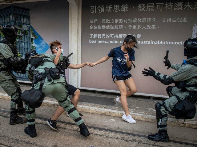 TOPSHOT - Police chase down a couple wearing facemasks in the central district in Hong Kong on October 5, 2019, a day after the city's leader outlawed face coverings at protests invoking colonial-era emergency powers not used for half a century. - Masked pro-democracy protesters marched through Hong Kong in …