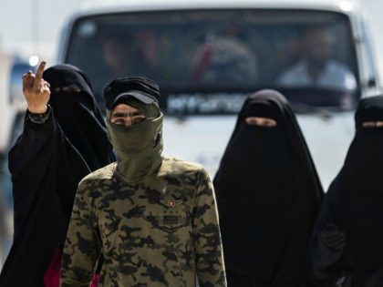 TOPSHOT - An internal security patrol member escorts women, reportedly wives of Islamic State (IS) group fighters, in the al-Hol camp in al-Hasakeh governorate in northeastern Syria, on July 23, 2019. - Stabbing guards, stoning aid workers and flying the Islamic State group's black flag in plain sight: the wives …
