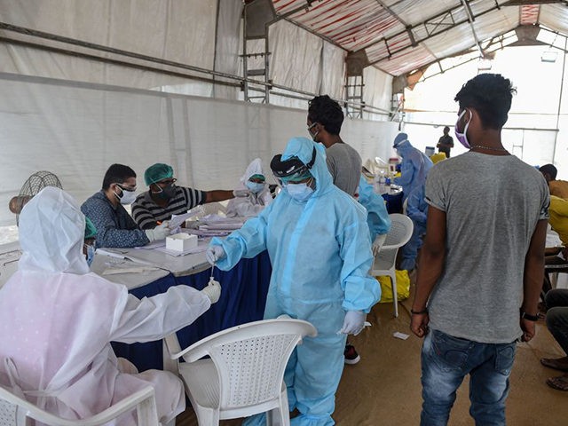Two health workers wearing Personal Protective Equipment (PPE) suits (L and C) collect a s