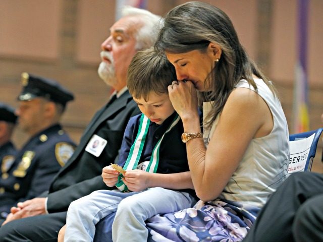 Lisa Tuozzolo, widow of deceased New York Police Department Sgt. Paul Tuozzolo, weeps as her son Austin looks at the NYPD's Medal of Honor he accepted posthumously for his father during the New York Police Department's Medal Day honoring police officers and their families who put their lives on the …