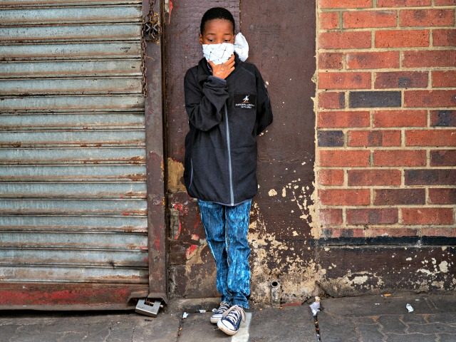A young boy wearing a makeshift mask waits in line to access a grocery store in the Hillbr