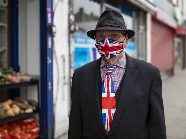 LONDON, UNITED KINGDOM - JUNE 12: A an walks down a high street in East London wearing a matching Union Jack tie and face mask on June 12, 2020 in London, England. As the British government further relaxes Covid-19 lockdown measures in England, this week sees preparations being made to …