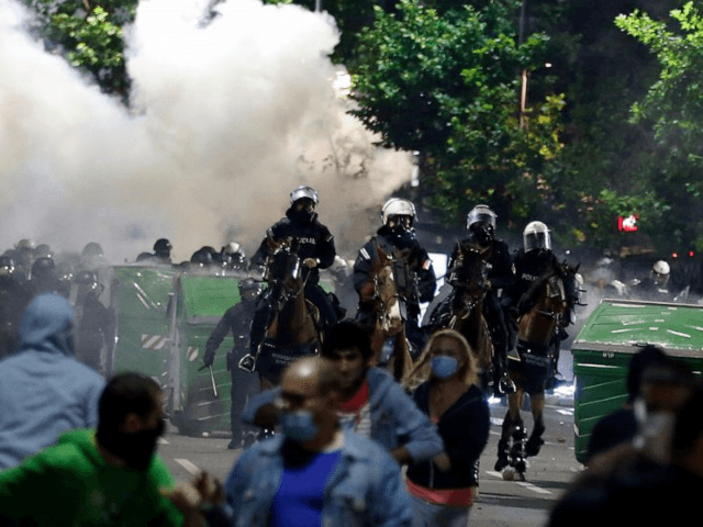 Sebian police officers disperse protesters in front of Serbian parliament building in Belgrade, Serbia, Wednesday, July 8, 2020. Thousands of people protested the Serbian president's announcement that a lockdown will be reintroduced after the Balkan country reported its highest single-day death toll from the coronavirus Tuesday. (AP Photo/Darko Vojinovic)