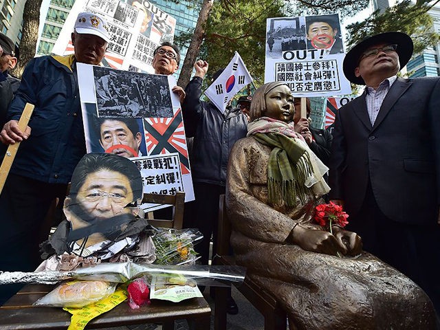 South Korean protestors place a damaged portrait (L) of Japan's Prime Minister Shinzo Abe