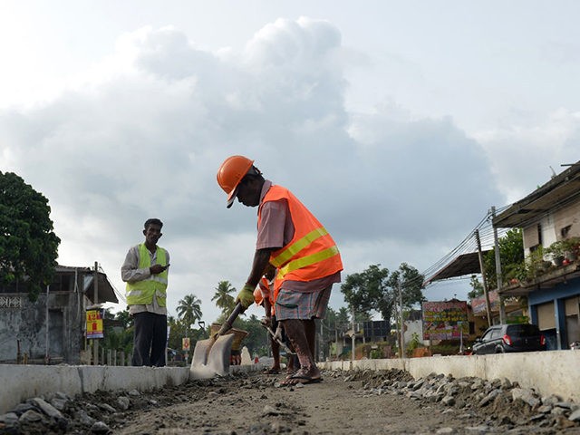 Sri Lankan road construction workers construction labourers works along a road in Colombo on August 5, 2018. - Sri Lanka's central bank on August 3 announced it had secured a $1 billion Chinese loan as the island, a key link in Beijing's ambitious Belt and Road initiative, develops closer relations …