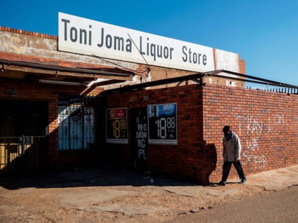 A man walks past a closed liquor shop in Soweto, on July 13, 2020. - South African President Cyril Ramaphosa on July 12, 2020 re-imposed a night curfew and suspended alcohol sales as COVID-19 coronavirus infections spiked and the health system risked being overwhelmed. (Photo by Michele Spatari / AFP) …