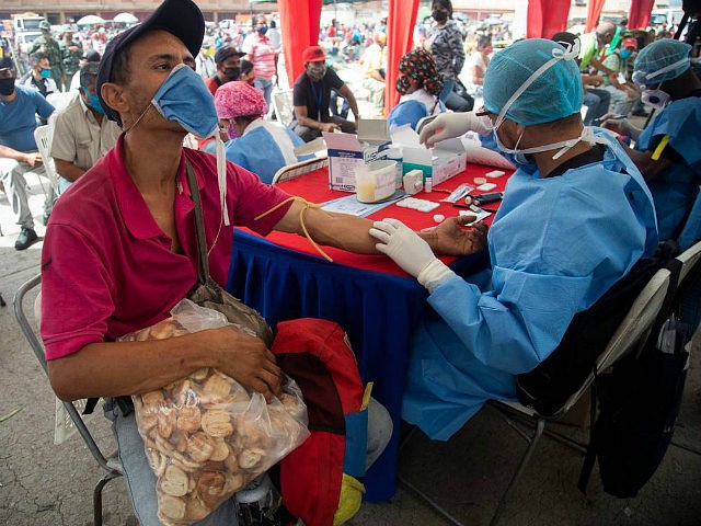 A health worker takes a blood sample for a quick COVID-19 test from man who works selling cookies at the Coche food market in Caracas, Venezuela, Tuesday, June 23, 2020. Health authorities tested people arriving at the market as a preventive measure to help curb the spread of the new …