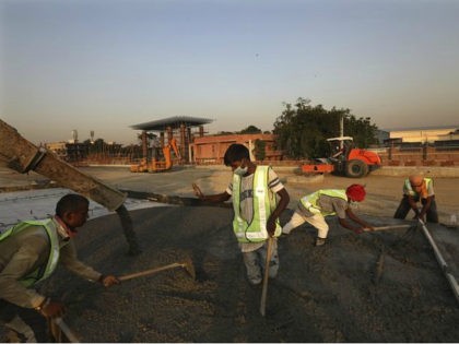 Road construction workers build a toll plaza on a highway in Ghaziabad, on the outskirts o