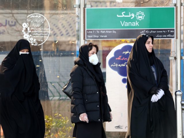 People wearing protective masks stand at a bus station in the Iranian capital Tehran on Ma