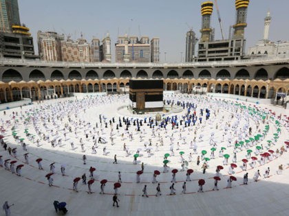 TOPSHOT - A picture taken on July 29, 2020 shows pilgrims holding coloured umbrellas along matching coloured rings separating them as a COVID-19 coronavirus pandemic measure while circumambulating around the Kaaba, Islam's holiest shrine, at the centre of the Grand Mosque in the holy city of Mecca, at the start …