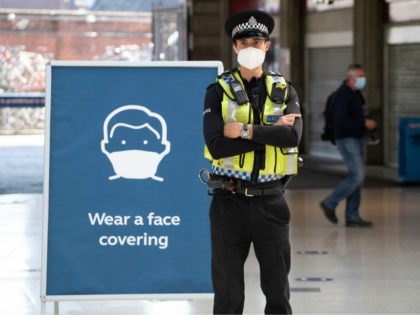 A police officer wears a face mask as he stands on the concourse at Waterloo Station in London on June 15, 2020 after new rules make wearing face coverings on public transport compulsory while the UK further eases its coronavirus lockdown. - New coronavirus pandemic rules coming into force on …