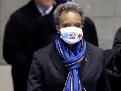 Chicago Mayor Lori Lightfoot, left, wears a mask as she heads to a news conference in Hall