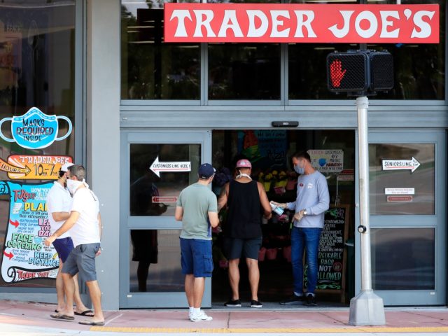MIAMI BEACH, FL - APRIL 14: A store associate distributes hand sanitizer to customers as they enter the Trader Joe's store in South Beach on April 14, 2020 in Miami Beach, Florida. The city of Miami Beach put in place an emergency measure requiring all customers and employees at grocery …