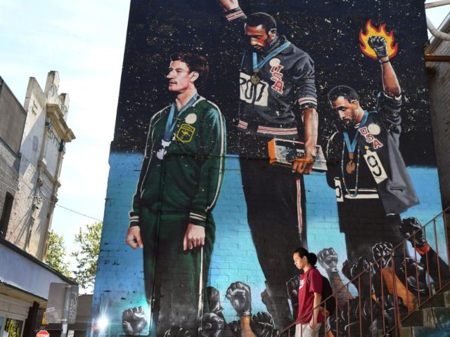 A photo taken in Melbourne on October 8, 2018, shows a man walking past a giant mural of A