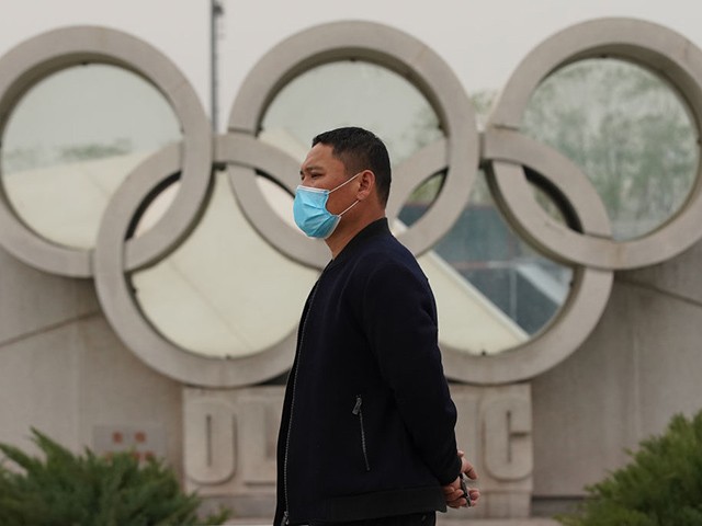 BEIJING, CHINA - MARCH 25: A Chinese man wears a protective mask as he walks past the Olympics rings at the Olympic park on March 25, 2020 in Beijing, China. The 2020 Tokyo Olympics have been postponed to no later than the summer of 2021 because of the coronavirus (COVID-19) pandemic sweeping the globe, the International Olympic Committee announced on March 24. (Photo by Lintao Zhang/Getty Images)
