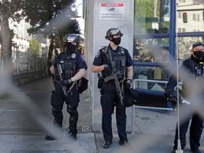 Seattle Police officers hold weapons as they stand guard outside the East Precinct Building, Sunday, July 19, 2020 in Seattle. Protesters broke windows at the building earlier in the afternoon. (AP Photo/Ted S. Warren)