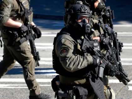 Seattle SWAT officers arrive as police and protesters clash following the "Youth Day of Action and Solidarity with Portland" demonstration in Seattle, Washington on July 25, 2020. - Police in Seattle used flashbang grenades and pepper spray Saturday against protesters who set fire to construction trailers outside a youth jail, …