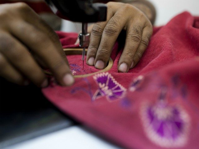 An Indian labourer sews patterns at the April Cornell clothing factory in Noida on the outskirts of New Delhi on October 16, 2012. The April Cornell company exports 50 percent of their clothing and linen production to the USA and Canada, and the rest to European Union countries. India's industrial …