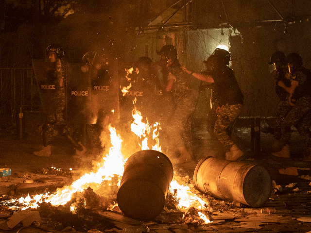 Riot police advance to push back anti-government protesters, during a protest against the political elites who have ruled the country for decades, in Beirut, Lebanon, Friday, Aug. 7, 2020. (AP Photo/Hassan Ammar)