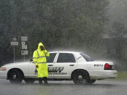 A Cameron Parish Sheriff deputy wipes his face as he mans a roadblock in the rain on LA 27 while residents evacuate Cameron in Lake Charles, La., Wednesday, Aug. 26, 2020, ahead of Hurricane Laura. (AP Photo/Gerald Herbert)