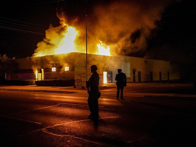 Police stand near a department of corrections building that was on fire during protests, Monday, Aug. 24, 2020, in Kenosha, Wis., sparked by the shooting of Jacob Blake by a Kenosha Police officer a day earlier. (AP Photo/Morry Gash)