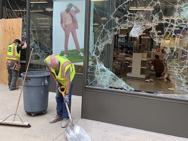 A worker shovels broken glass outside of Nordstrom Rack in downtown Minneapolis on Thursday, Aug. 27, 2020. An emergency curfew has expired and downtown Minneapolis was calm after unrest broke out overnight following what authorities said was misinformation about the suicide of a Black homicide suspect.(AP Photo/Jeff Baenen)