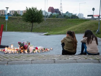 Two girls sit next to a makeshift memorial at the site where a twelve year old girl was shot near a petrol station in Botkyrka, south of Stockholm, on August 2, 2020. - The young girl with gunshot injuries was taken to hospital but later succumbed to her wounds. (Photo …