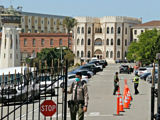 This July 9, 2020, file photo shows a correctional officer closing the main gate at San Quentin State Prison in San Quentin, Calif. California is giving more than 100,000 state inmates earlier release dates in its latest response to the pandemic, building on earlier steps that together could free nearly …